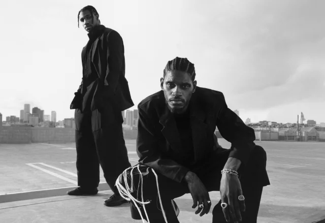 A$AP Nast and Noah Lyles stand on an LA rooftop in a black-and-white photo, dressed in adidas Y-3 and gazing intently into the camera.