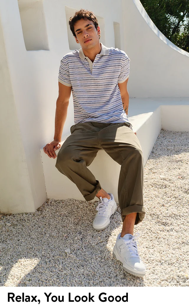 A man relaxing in a stripe polo and dark khaki pants.