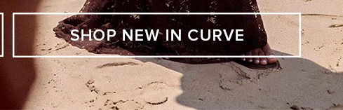 SHOP NEW IN CURVE banner: Woman's foot in sandal on sandy beach, promoting new arrivals for women's plus size fashion & curve clothing.