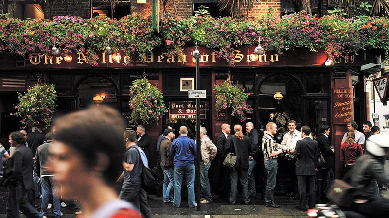 Image description: People standing outside a pub in London.