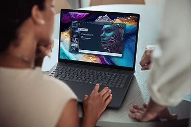 An over-shoulder view of two people using a Dell laptop computer to create a presentation.