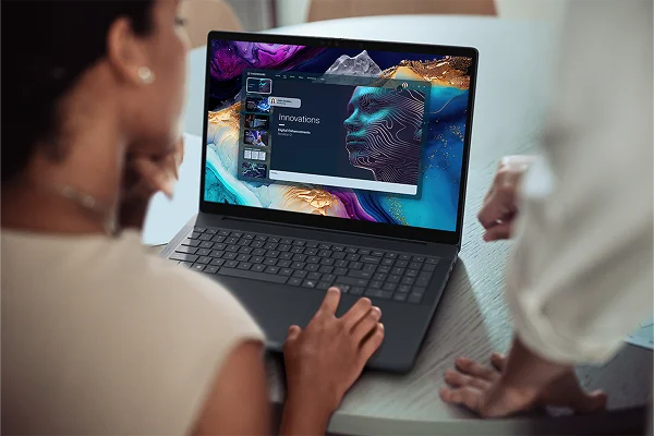 An over-shoulder view of two people using a Dell laptop computer to create a presentation.
