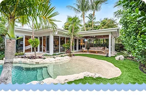 Contemporary tropical home with an open patio, palm trees, and a lagoon-style pool with rock accents.