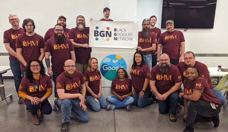 Photo of two rows of people wearing shirts that say “BHM” looking into the camera and smiling. The people in the center of the back row are holding a sign that says “BGN, Black Googler Network.”