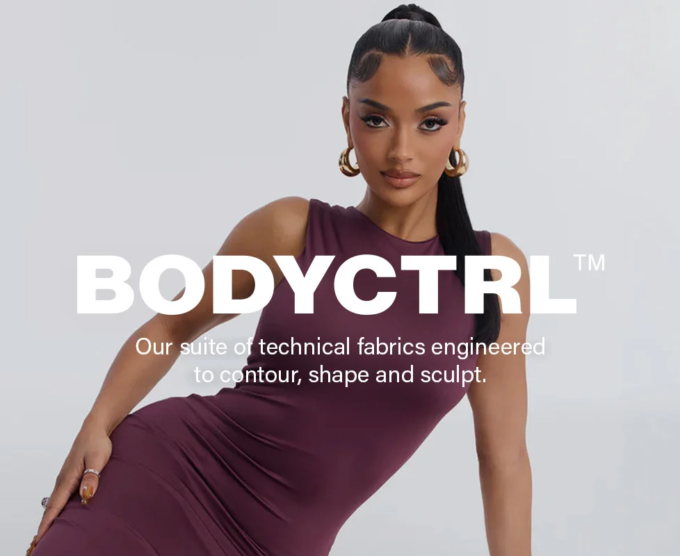 Woman models a plum BODYCTRL™ bodycon dress, highlighting new technical fabrics for sculpting and shaping performance wear.