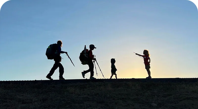 Silhouettes of one adult and three kids walking.
