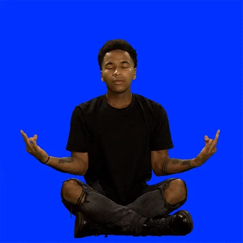 A man sitting in meditation position with a rainbow appearing on top saying, "Make this year suck less."
