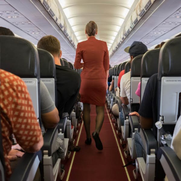 A flight attendant walks down the aisle of a plane