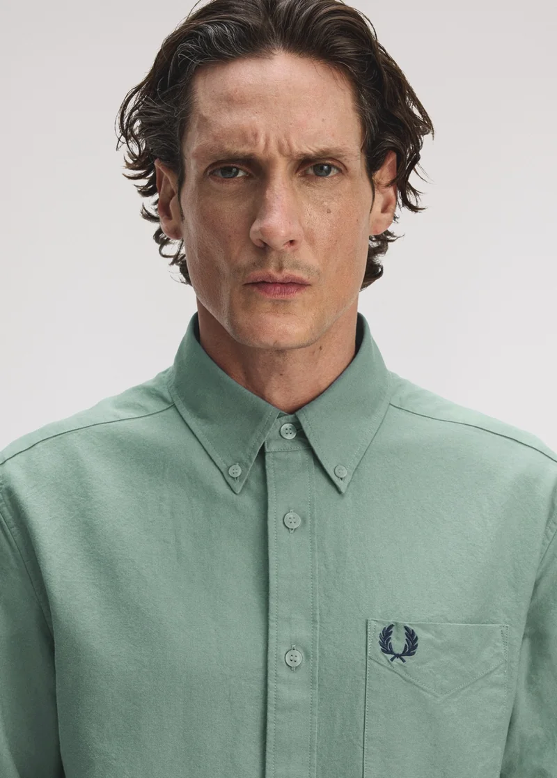 A close up shot of a male model wearing a Fred Perry Oxford Shirt in Bay Leaf