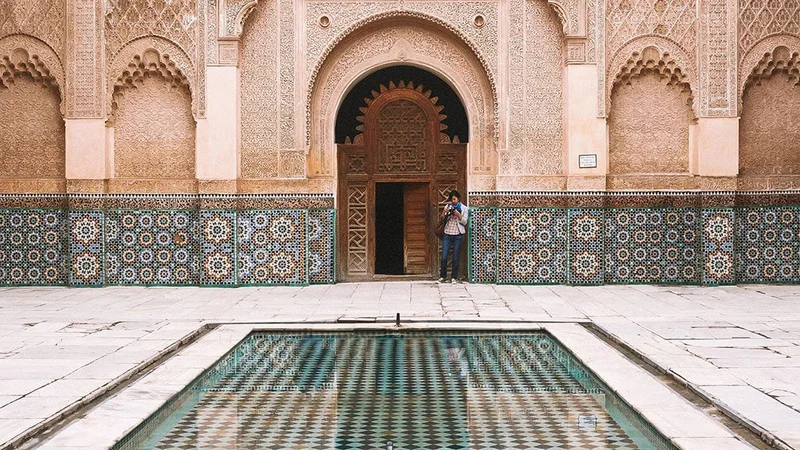Image description: Woman visiting Ben Youssef Madrasa courtyard in Marrakesh, Morocco
