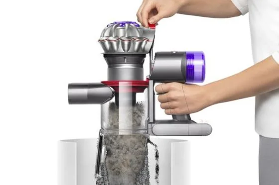 A person hygienically empties their Dyson Car+Boat vacuum into their household waste.