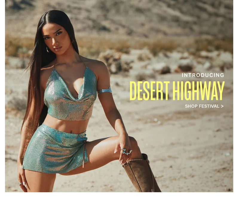 Woman in shimmering silver-teal metallic halter top and mini skirt, brown boots, posing in a desert. Introducing the Desert Highway festival fashion collection.