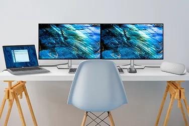 A desk with two Dell monitors, a laptop, wired speaker, wireless keyboard and mouse.
