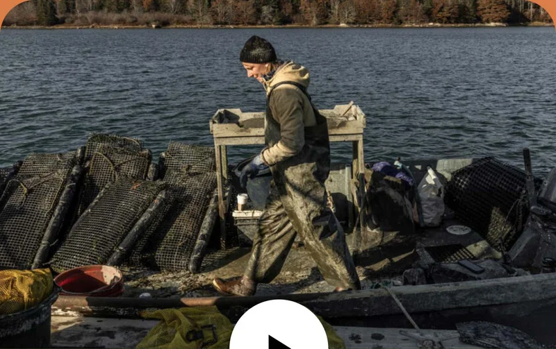 A person in dirty slickers walks on the deck of their small boat.