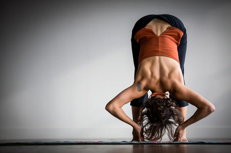 A woman folds into a standing forward bend, or uttanasana.