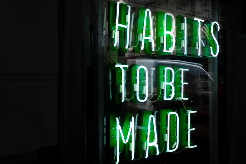 A neon green sign that says, “Habits to be made.”