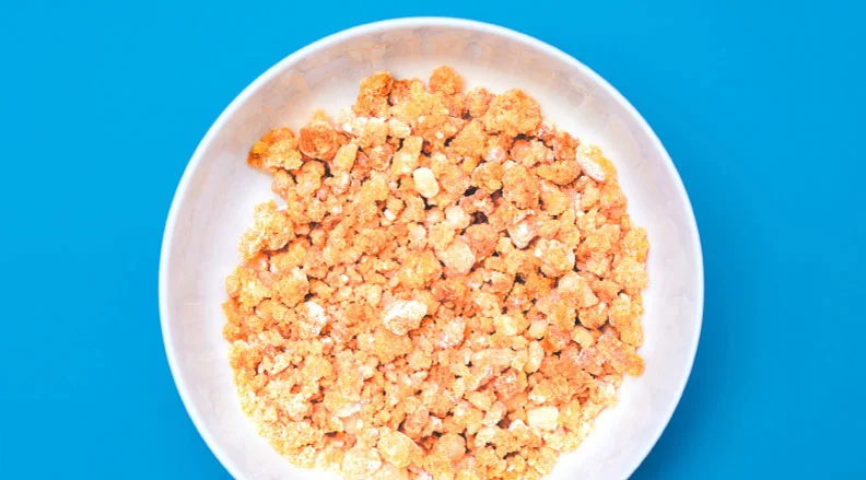 A bowl of orange, homemade fizzy candy mimicking pop rocks, with a close-up view of its bubbly, textured surface.