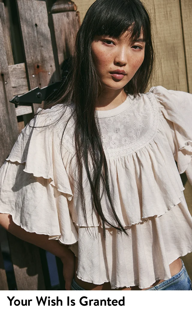 A woman wearing a tiered t-shirt with an embroidered mesh neckline.