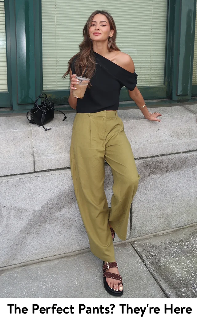 A woman wearing wide-leg pants with a one-shoulder top and platform sandals.