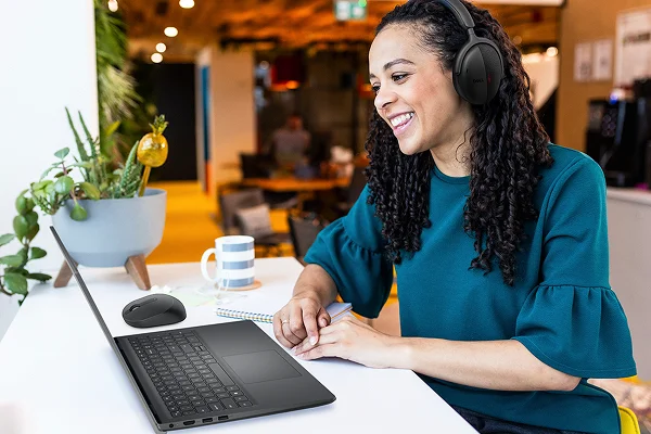A happy office worker engaged in a video call on a Dell laptop.