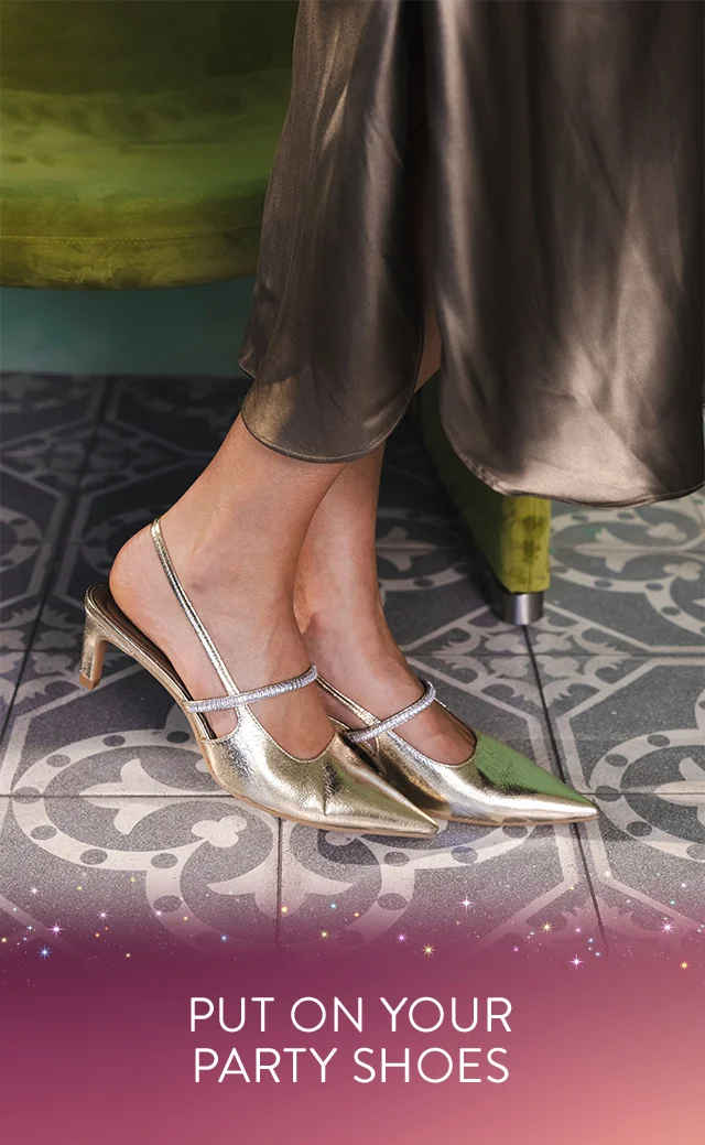 A woman wearing gold heels with crystal straps.