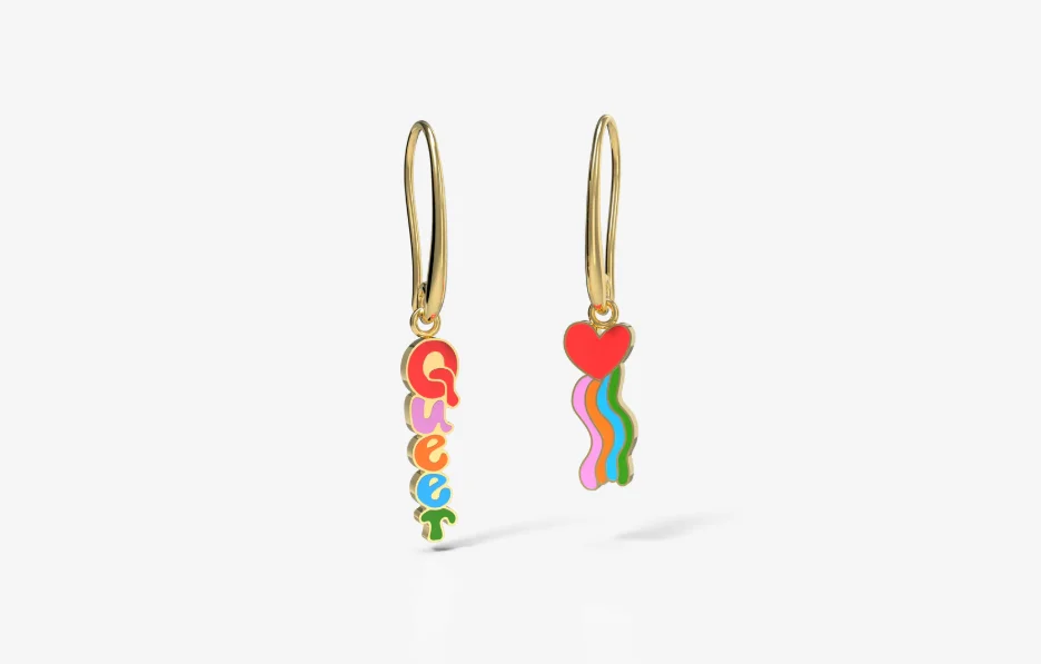 A pair of dangling earrings; one says “Queer” in rainbow letters, and the other is a heart with a rainbow