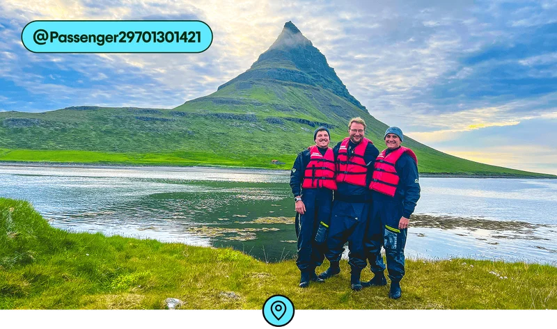 Image description: Three people with red lifevests posing in front of the Kirkjufell mountain, photo taken by @Passenger29701301421