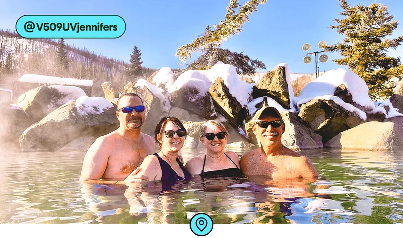 Image description: A group of four people submerged in a hot spring with snow-covered rocks behind them, photo taken by @V509UVjennifers