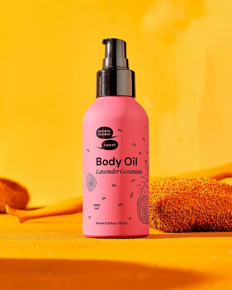 A pink bottle on a burnt sienna background with a barbie leg behind it
