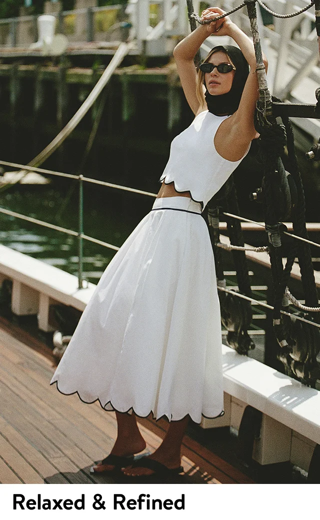 A woman wearing a white top with a scalloped hem and a matching skirt.