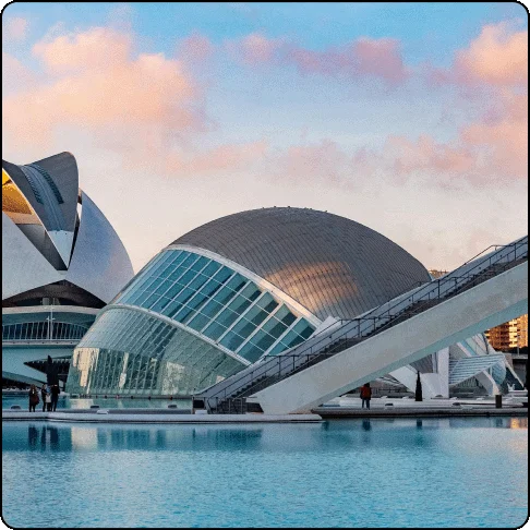 Image Description: Large glass and steel dome on top of water with soft pink clouds in the sky.