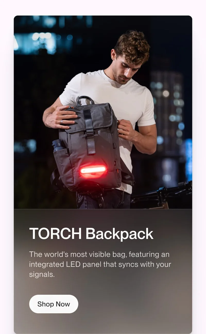 Person holding a TORCH backpack with illuminated rear LED panel at night, shown with copy about synced visibility and integrated signals