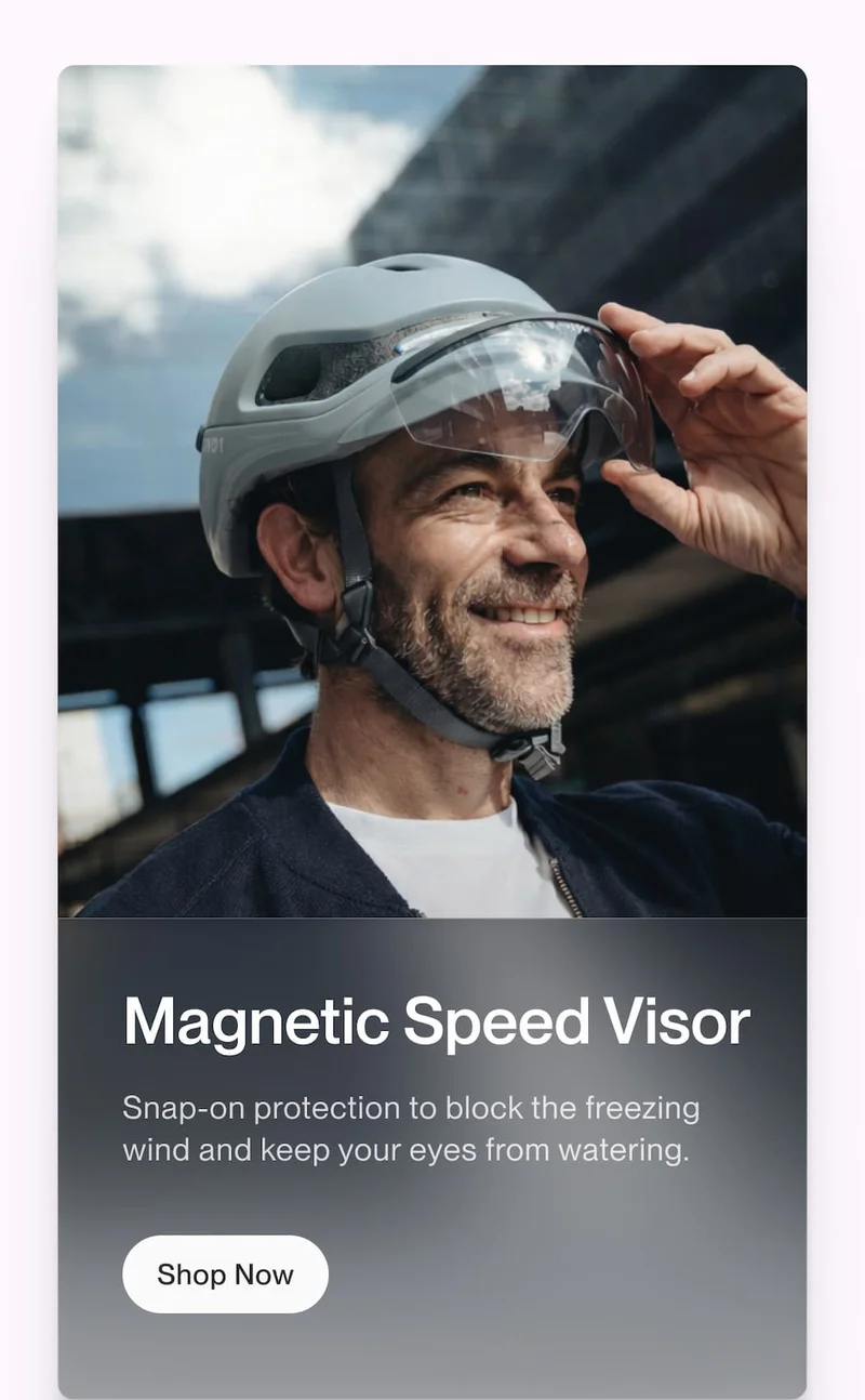 Smiling rider wearing a UNIT 1 helmet with magnetic speed visor attached, shown with copy about blocking wind and protecting eyes