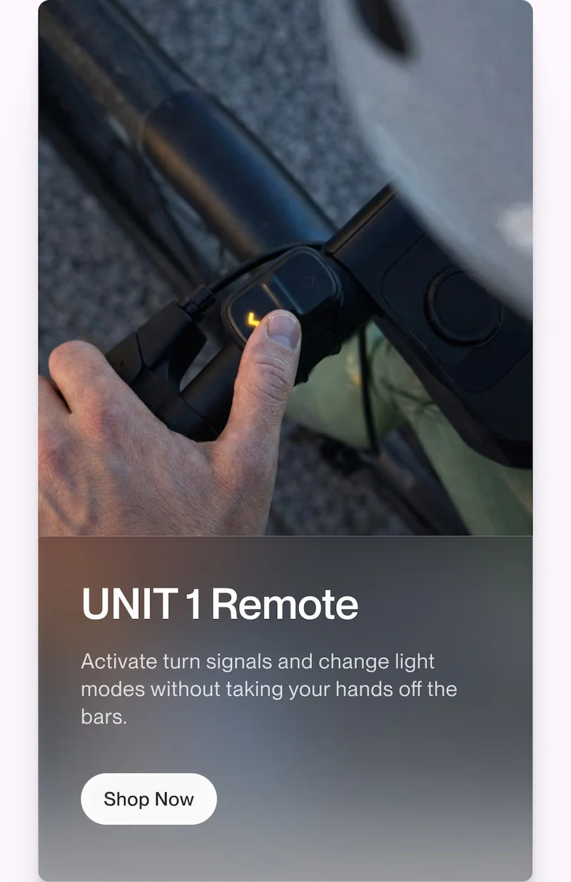 Close-up of a hand pressing the UNIT 1 remote on a handlebar, with copy about activating turn signals and changing light modes hands-free
