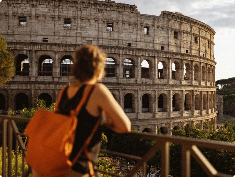 Image Description: A traveler admiring a view of the Colosseum in Rome at sunset