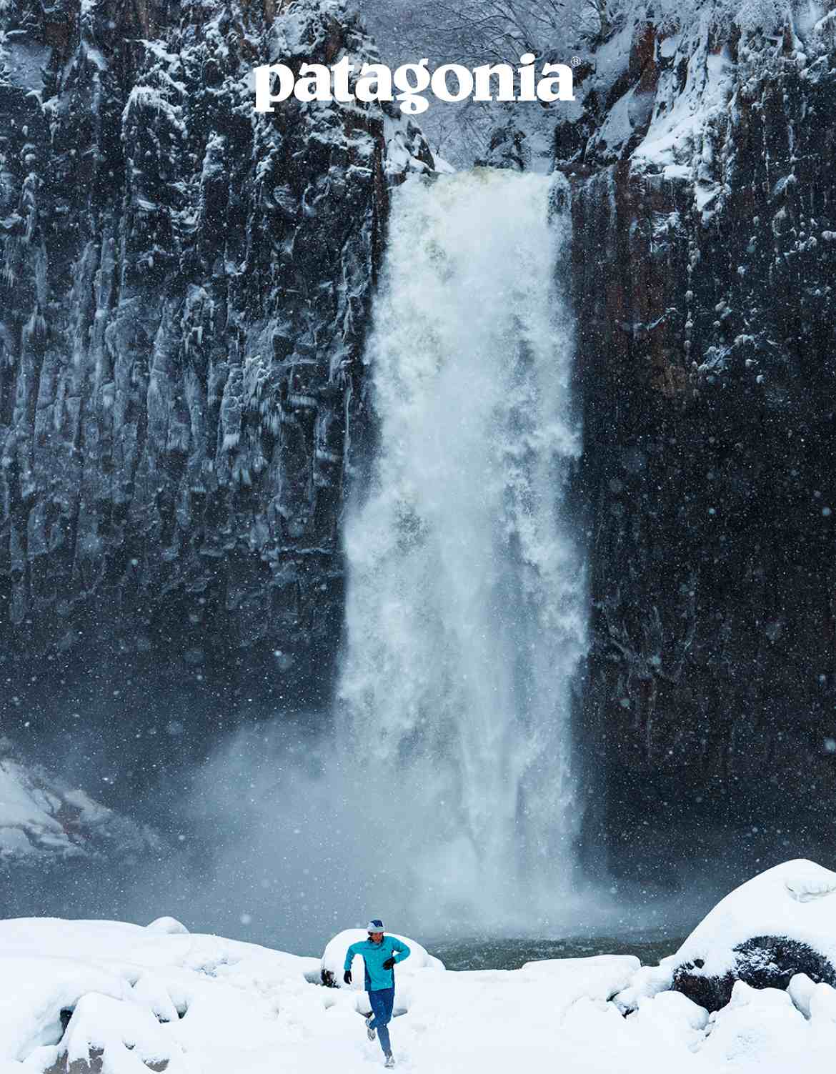 Patagonia. A runner on a snowy trail in front of a powerful waterfall.