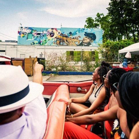 Image Description: A group of travelers admiring street art from a car in Little Havana, Miami
