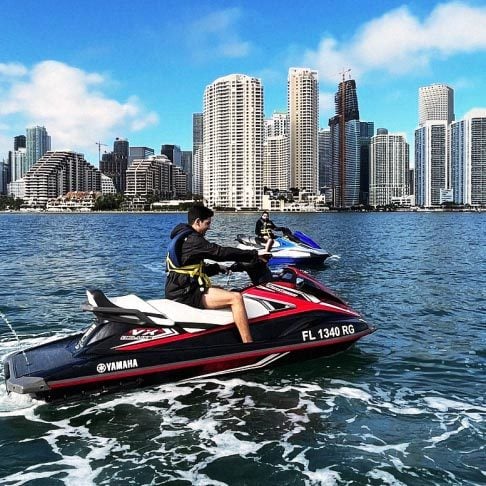 Image Description: Two male travelers jet skiing along Biscayne Bay, Miami