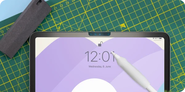 An iPad on a table with Paperlike's Cleaning Kit and an Apple Pencil (plus Paperlike's Grip) around it.