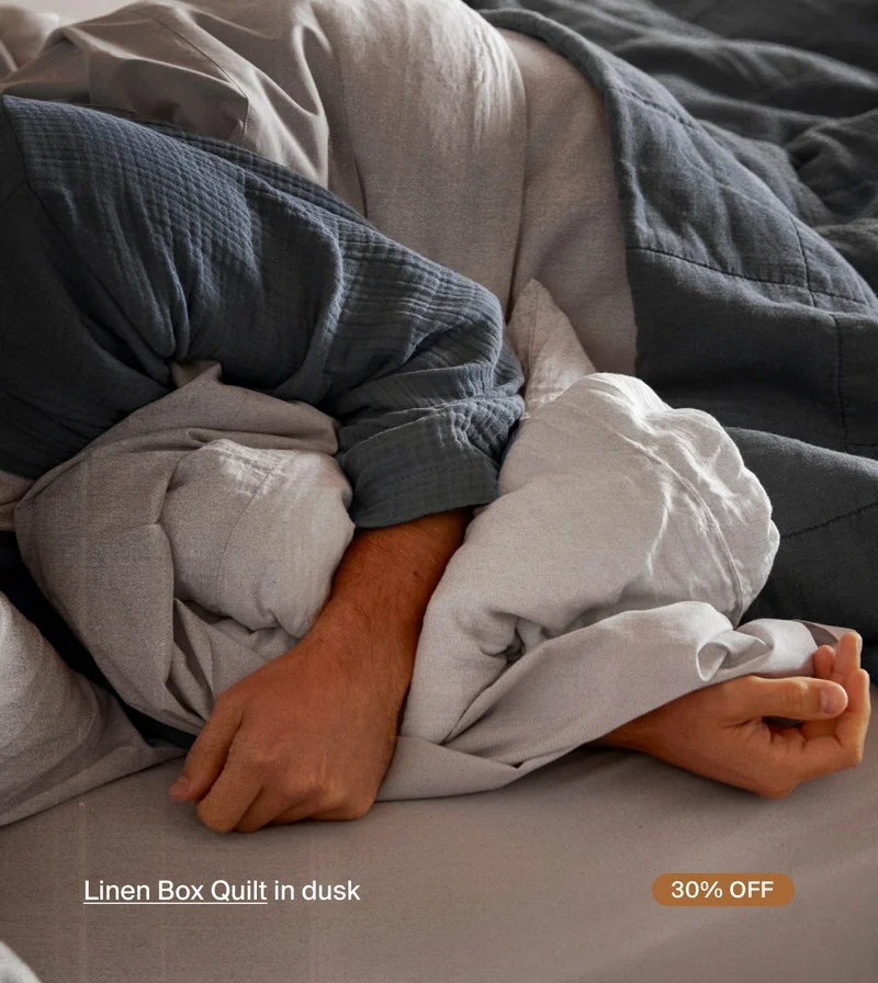Wearing blue robe in bed with grey sheets and blue comforter.