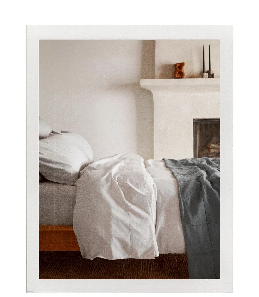 Bed styled in grey sheets and blue comforter.