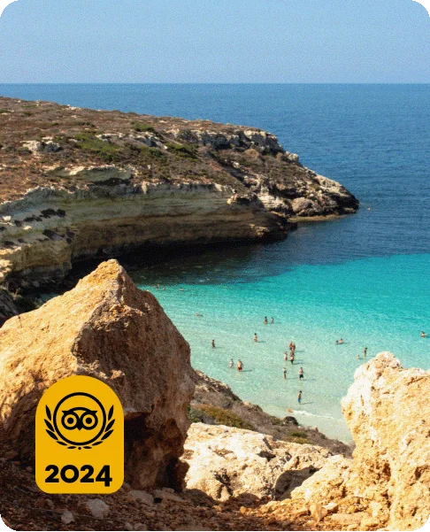 Image Description: People wading in a turquoise-blue ocean surrounded by cliffs. A gold Travelers’ Choice Awards Best of the Best 2024 badge is on the bottom left corner.