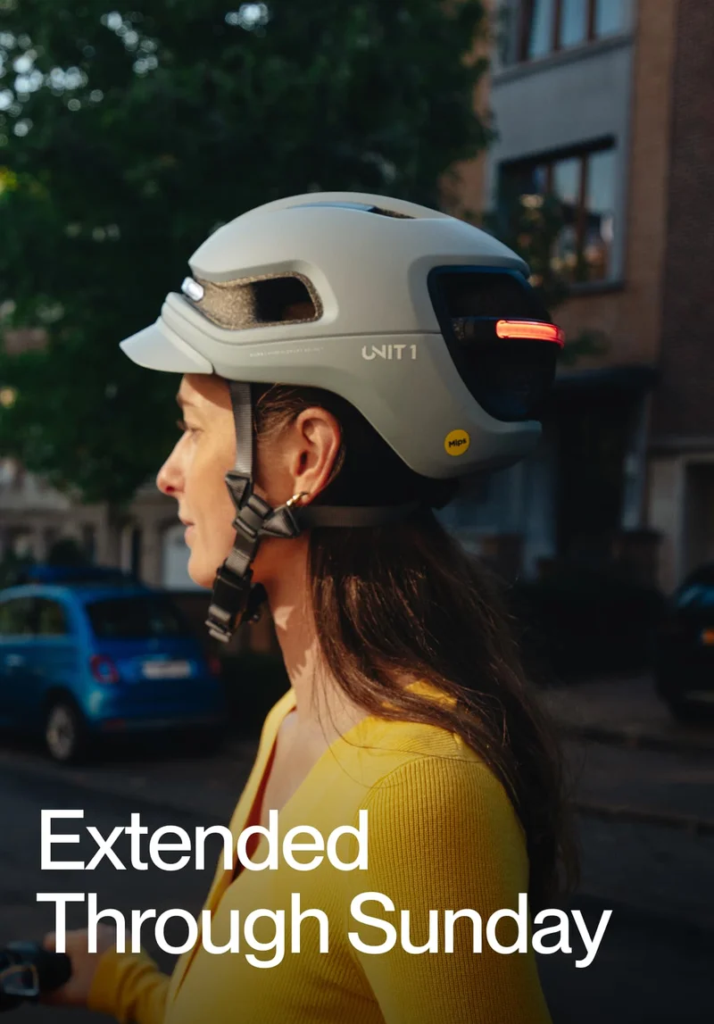 Woman riding an e-bike at sunset wearing the UNIT 1 AURA smart helmet — "Extended Through Sunday"