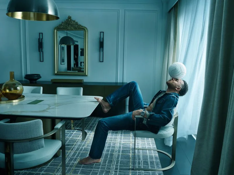 Image may contain: Kylian Mbappé, Person, Sitting, Clothing, Pants, Jeans, Adult, Chair, Furniture, Hosiery, and Sock