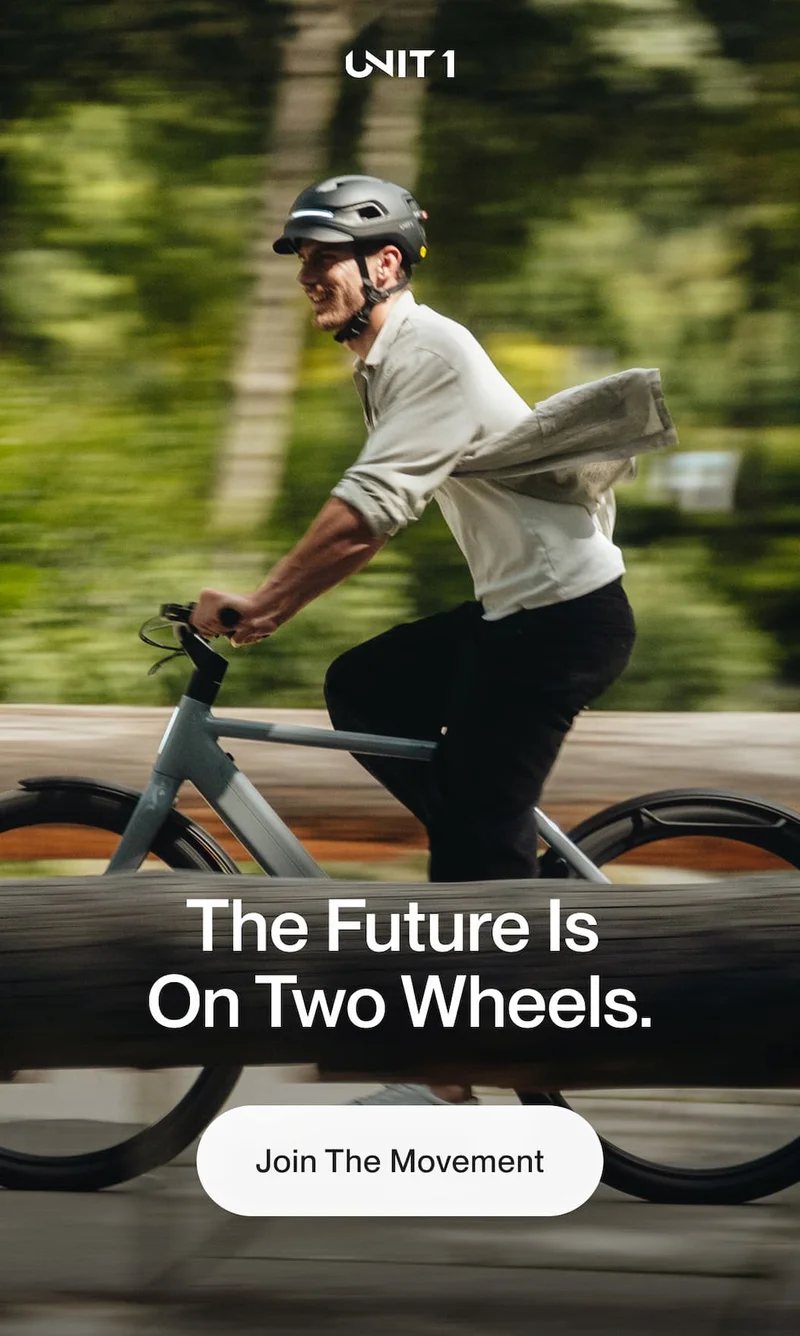 Cyclist riding through a green urban setting wearing a UNIT 1 smart helmet.