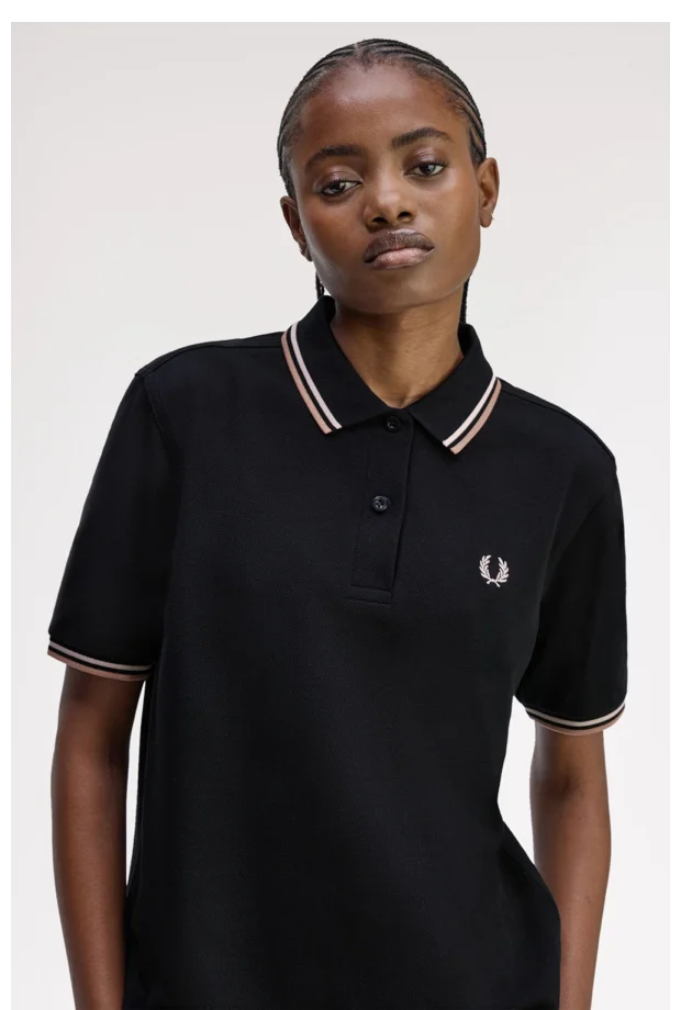 Female model wearing a Fred Perry Polo in Black / Silky Peach / Blossom Pink