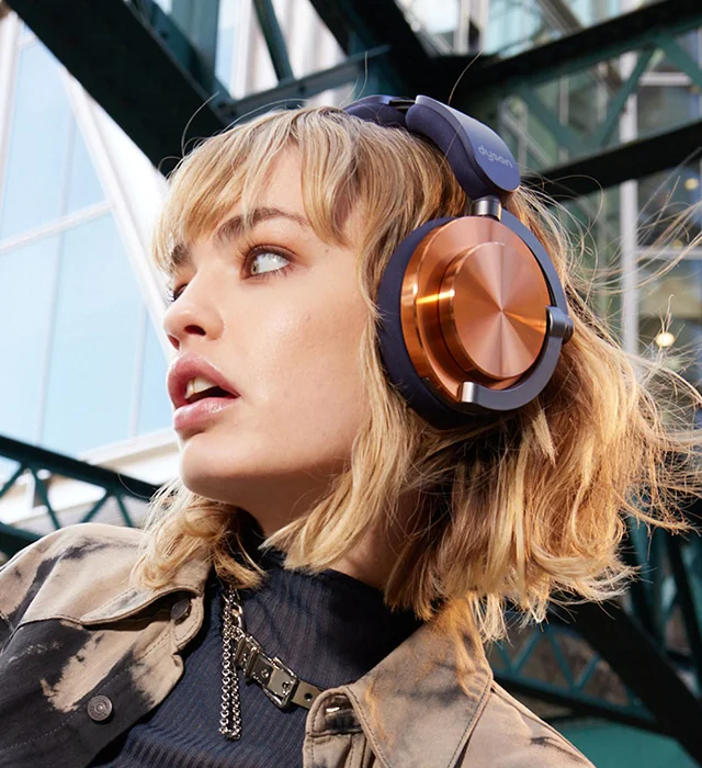 A model wearing Dyson OnTrac headphones in CNC Copper color combo