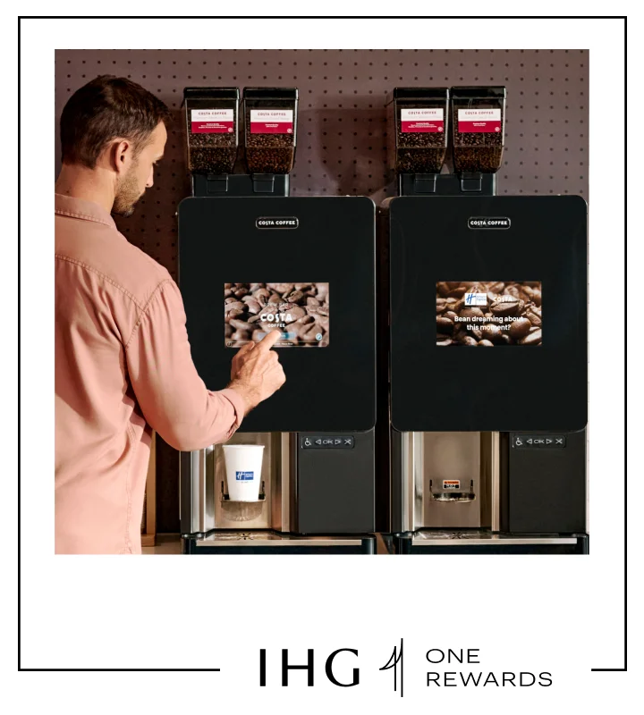 A man stands in front of a Costa Coffee machine, getting his morning brew.