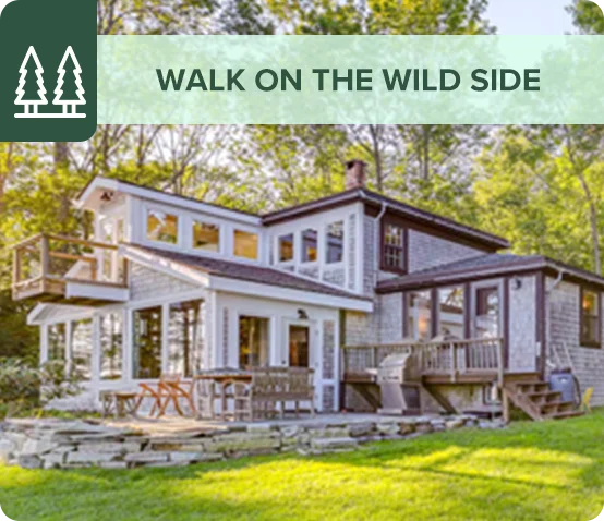 Contemporary cabin surrounded by a forest with outdoor seating and decks.