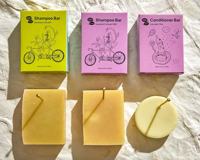 A collection of shampoo and conditioner bars set in a grid and pinned to the surface